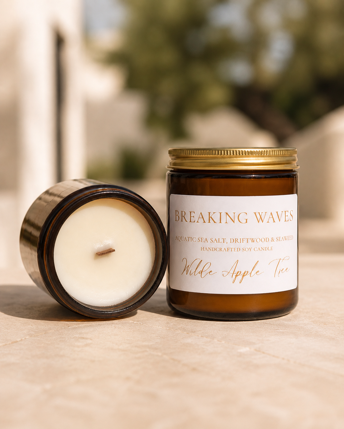 Wilde Apple Tree Breaking Waves medium soy candle in amber glass jar with lid removed showing natural wooden wick outdoors, aquatic sea salt driftwood and seaweed scent, handcrafted in Australia