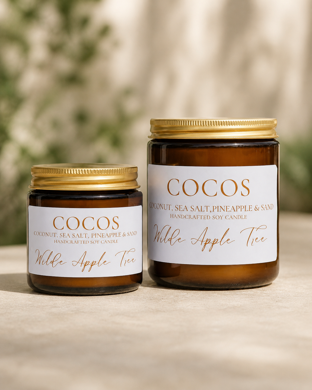 Wilde Apple Tree Cocos handcrafted soy candles in mini and medium amber glass jars side by side outdoors, coconut sea salt and pineapple scent, made in Australia