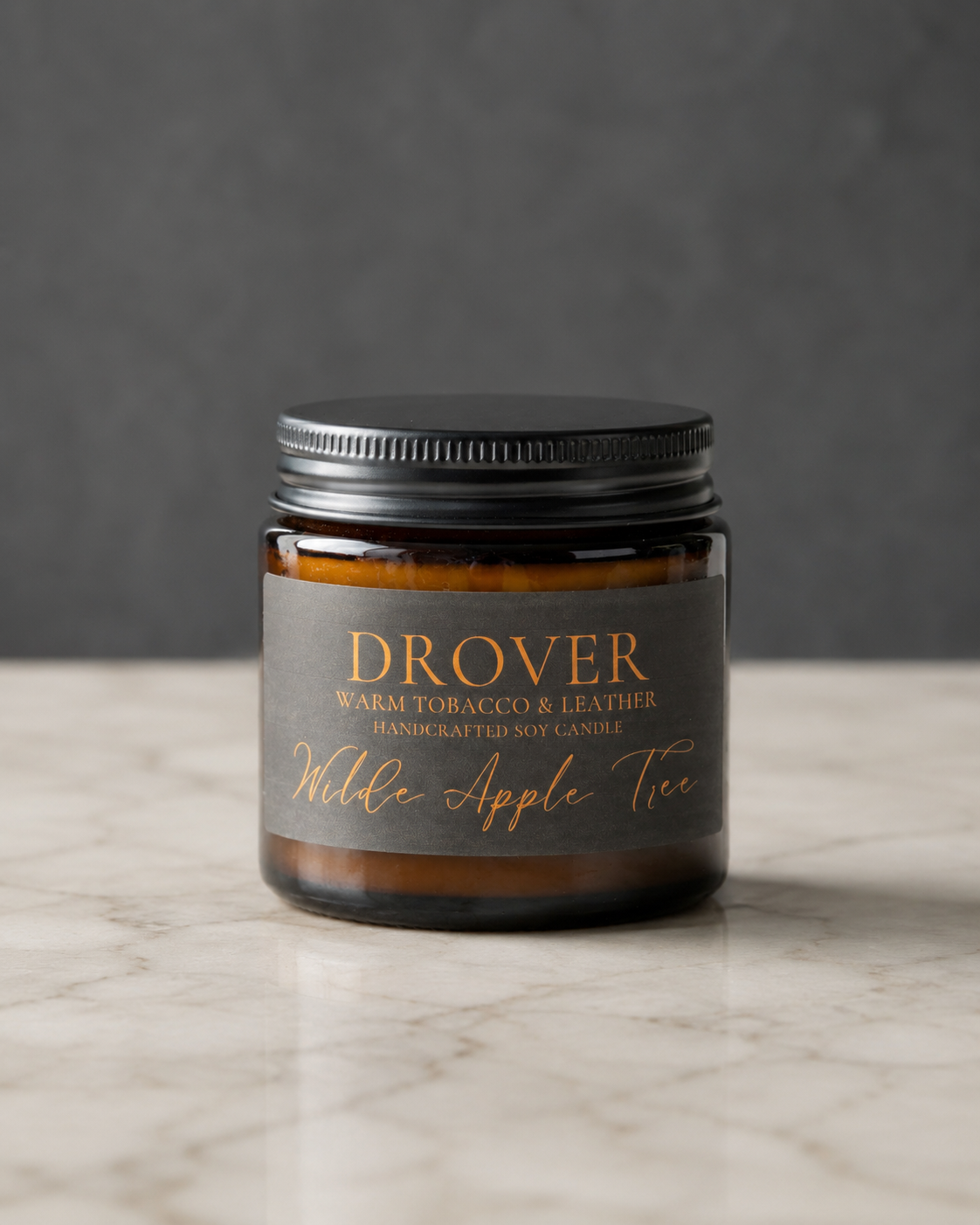 Wilde Apple Tree Drover mini soy candle in amber glass jar with black lid and charcoal label on marble surface, warm tobacco and leather scented handcrafted soy candle made in Australia