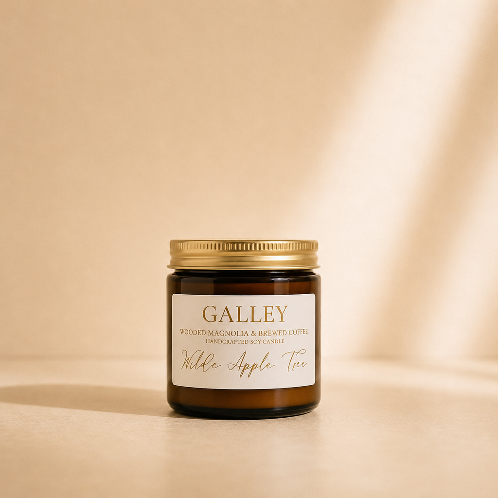 Wilde Apple Tree Galley mini soy candle in amber glass jar with gold lid in warm studio light with soft shadows, wooded magnolia and brewed coffee scented handcrafted soy candle made in Australia