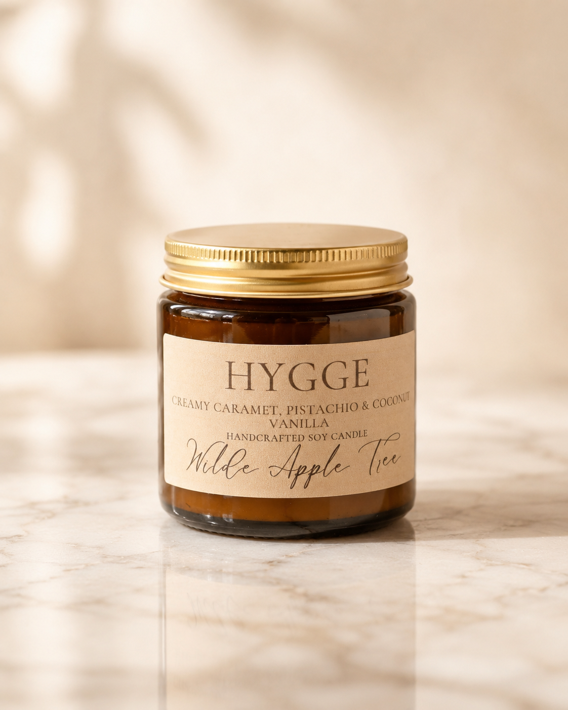 Wilde Apple Tree Hygge mini soy candle in amber glass jar with warm beige label on marble surface, creamy caramel pistachio coconut and vanilla scented handcrafted soy candle made in Australia