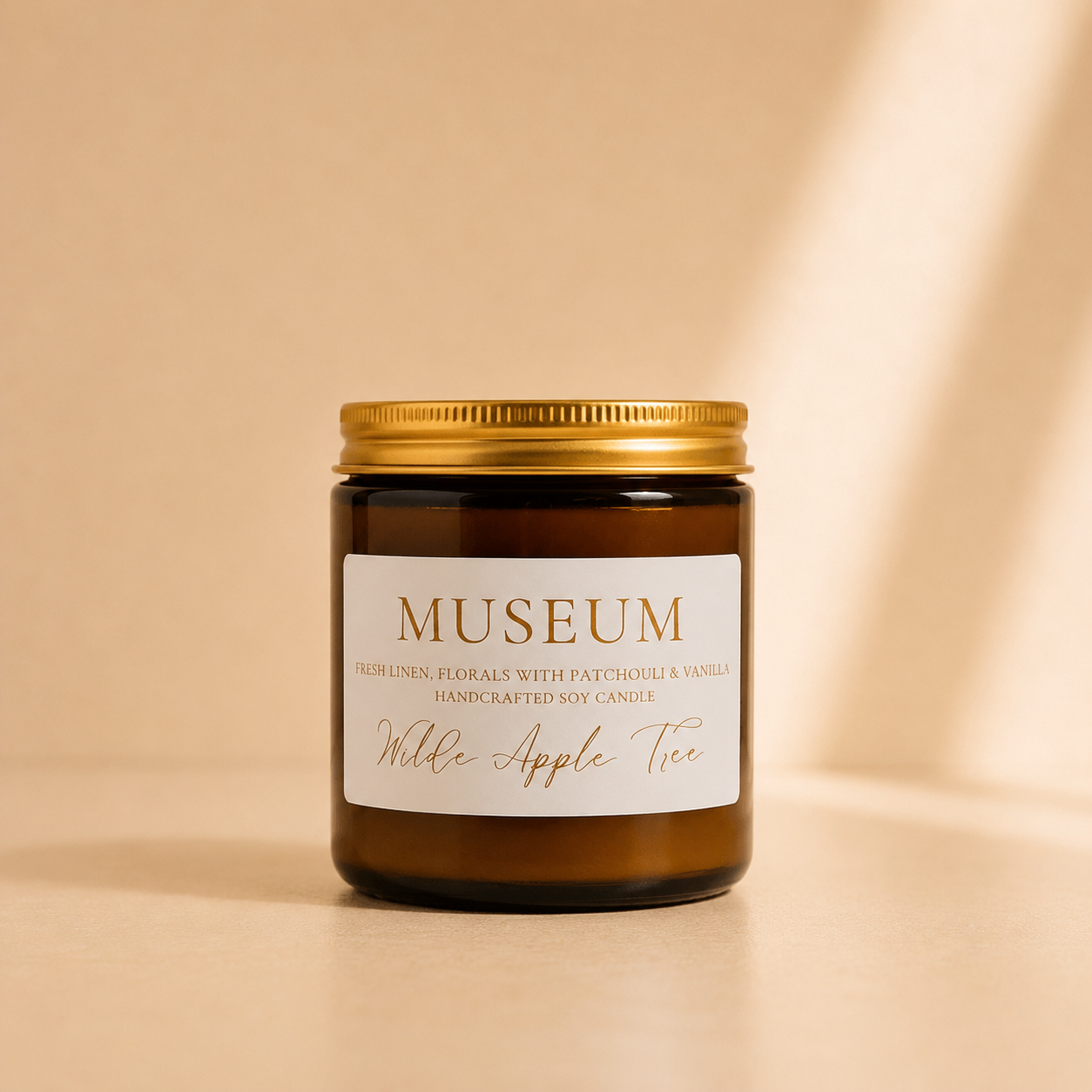 Wilde Apple Tree Museum medium soy candle in amber glass jar with gold lid in warm studio light, fresh linen florals patchouli and vanilla handcrafted soy candle made in Australia