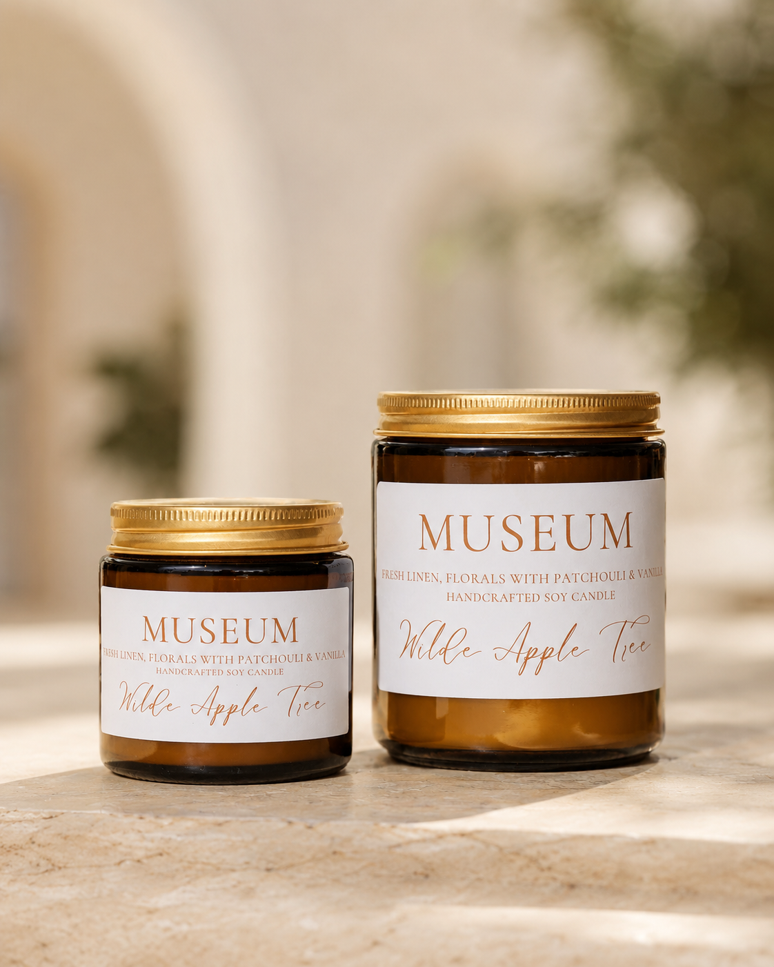 Wilde Apple Tree Museum handcrafted soy candles in mini and medium amber glass jars side by side in dappled natural light, fresh linen florals patchouli and vanilla scent, made in Australia