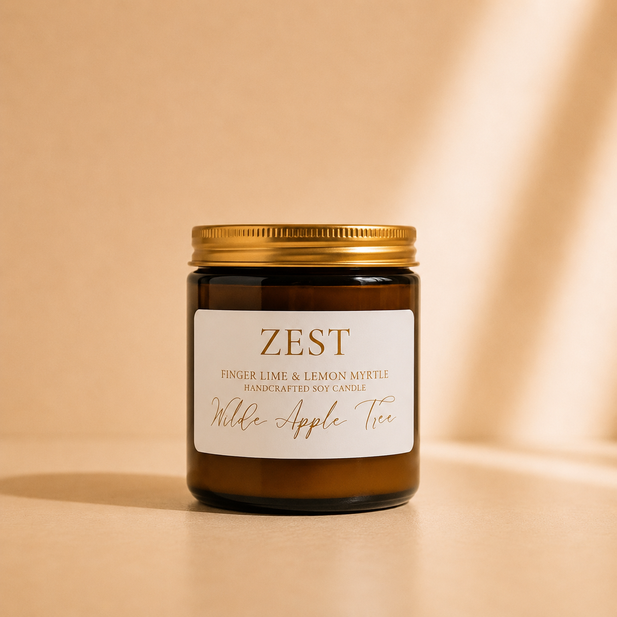 Wilde Apple Tree Zest medium soy candle in amber glass jar with gold lid in warm studio light, Australian finger lime and lemon myrtle handcrafted soy candle made in Australia